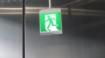 Japanese overhead small green exit sign with Running Man image moving through doorway